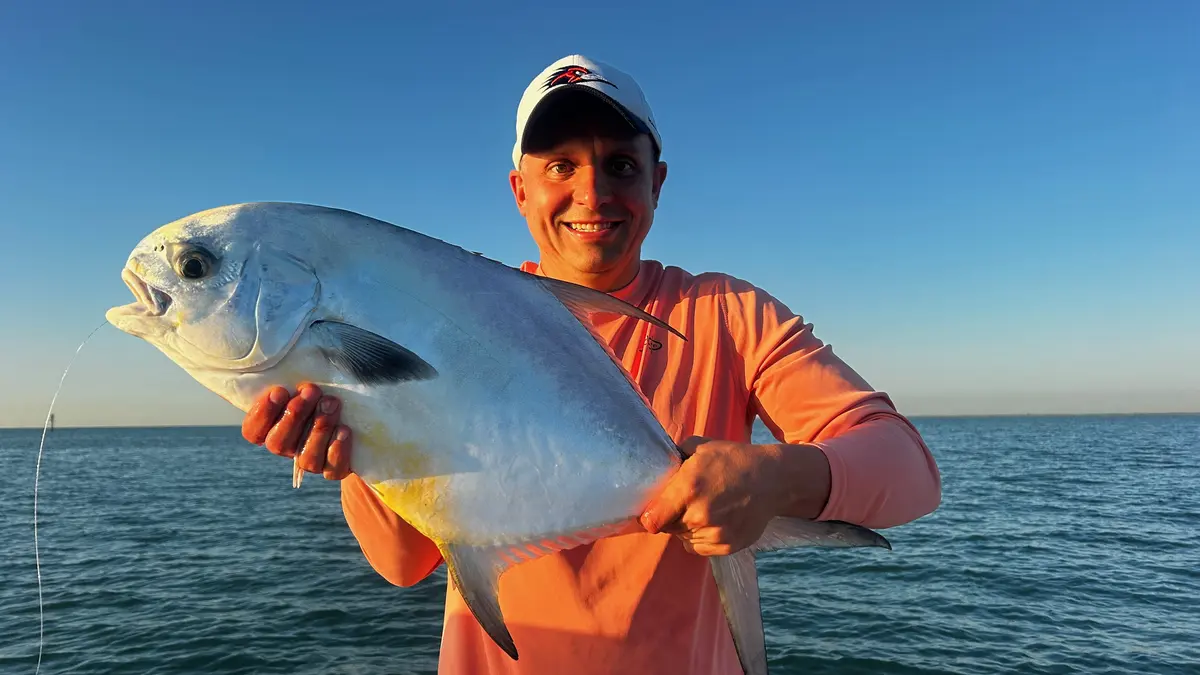 Happy angler holding a large permit caught on a Miami Bay Fishing Charter